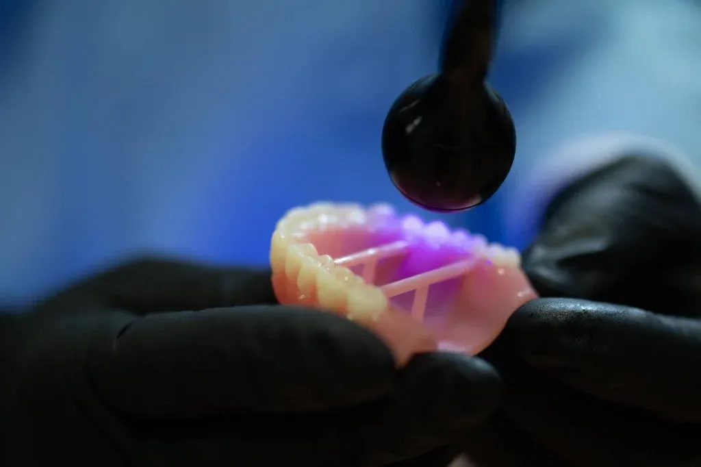 A technician post-processing a printed denture base