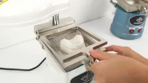 A technician trimming a thermoformed retainer to a scalloped margin