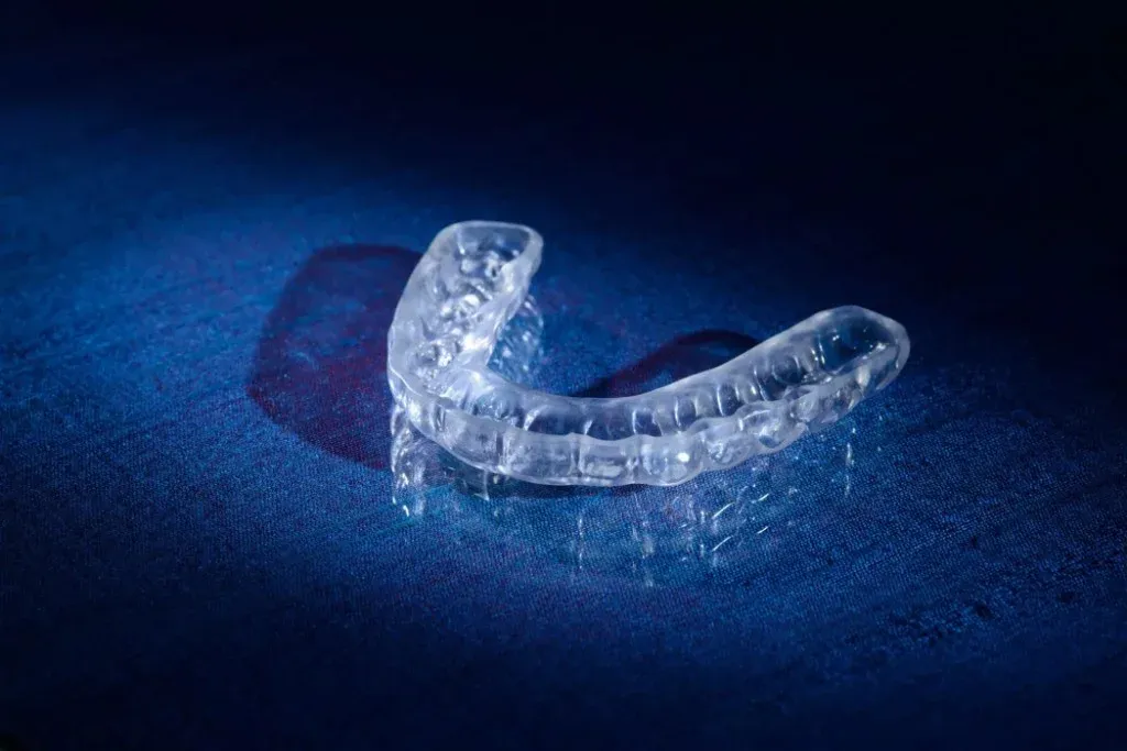 A worn occlusal appliance under bench light, facets and marking visible